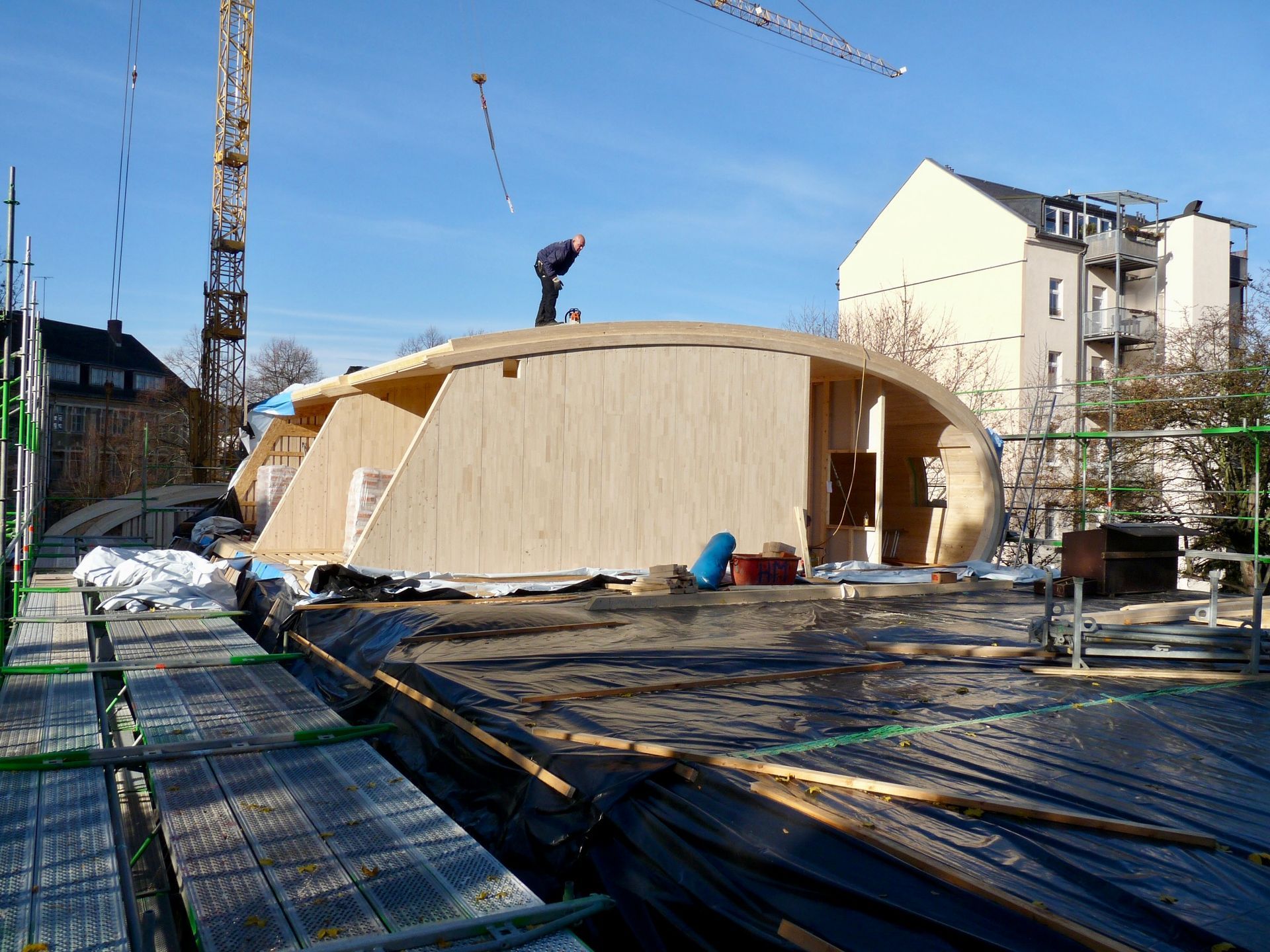 Rohbau der Kindertagesstätte während der Montage einer geschwungenen Holzkonstruktion.