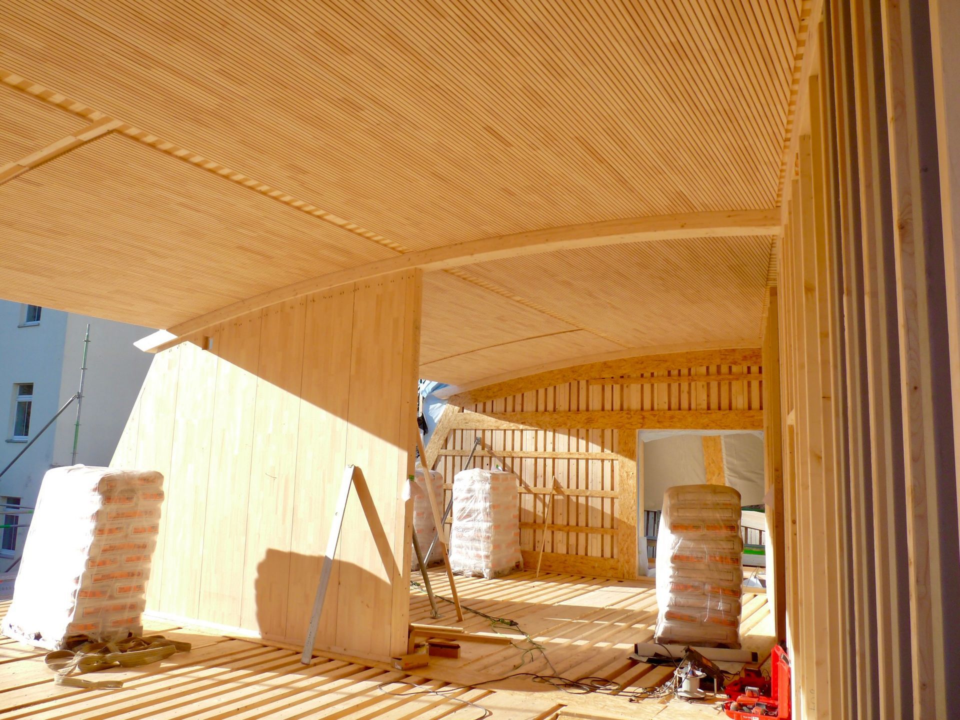Innenansicht mit freigelegter Holzstruktur und geschwungener Deckenkonstruktion.