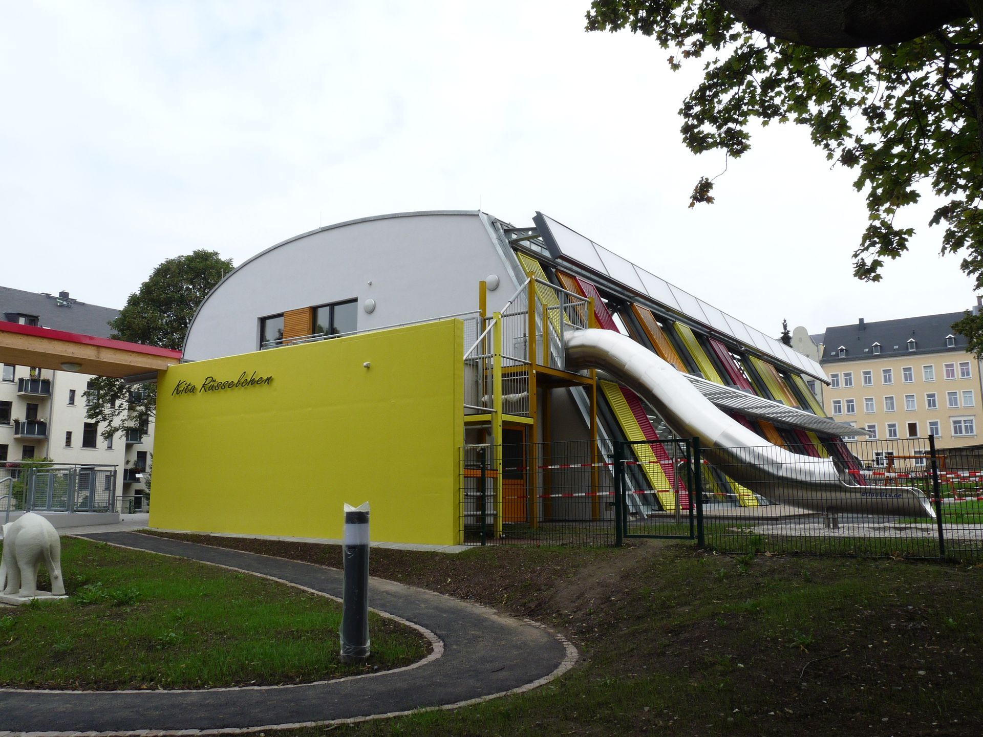 Moderne Kindertagesstätte mit geschwungener Gebäudeform und großem Außenspielbereich.