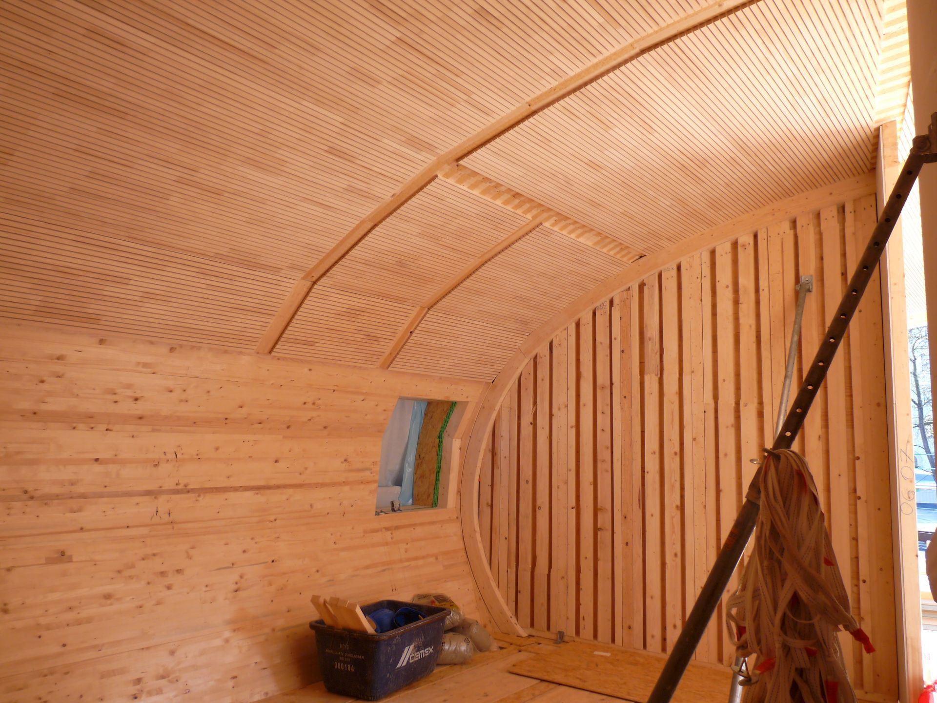 Detailaufnahme der gebogenen Holzdecke und Wandverkleidung der Kindertagesstätte.