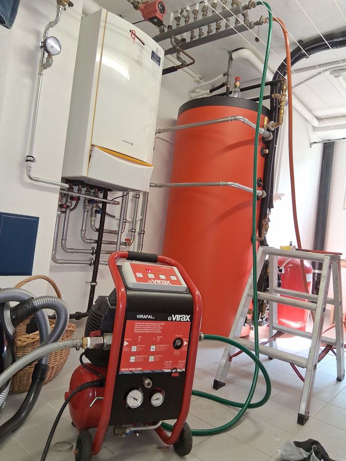 Un compresseur d'air est placé dans une pièce à côté d'un grand réservoir orange.