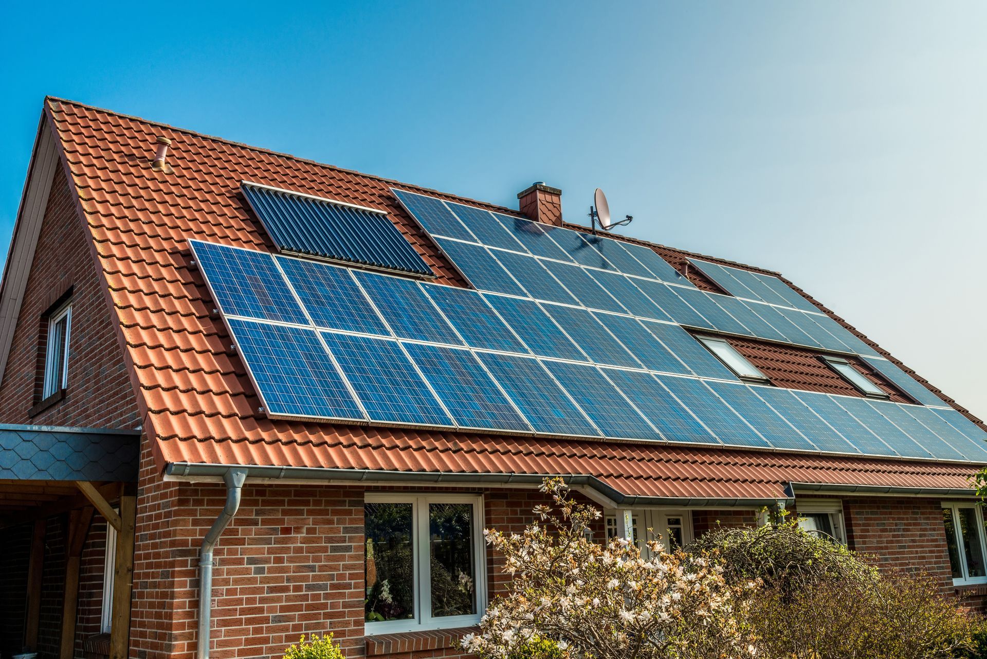Une maison en briques avec des panneaux solaires sur le toit.