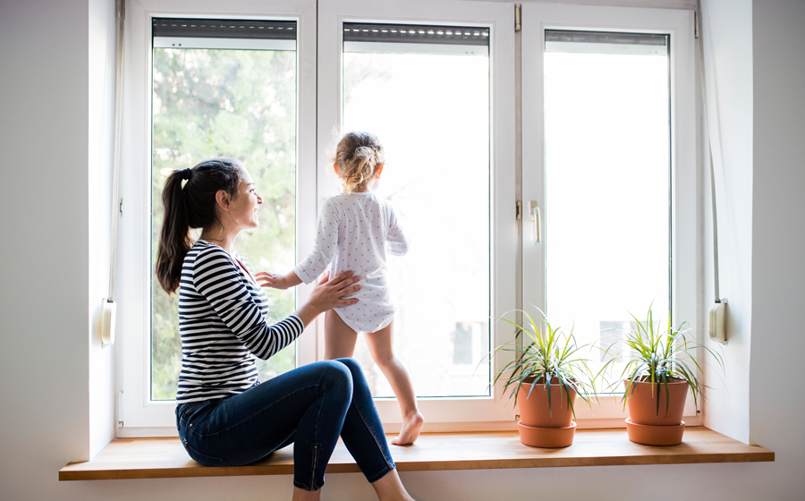 Femme avec un enfant devant une fenêtre