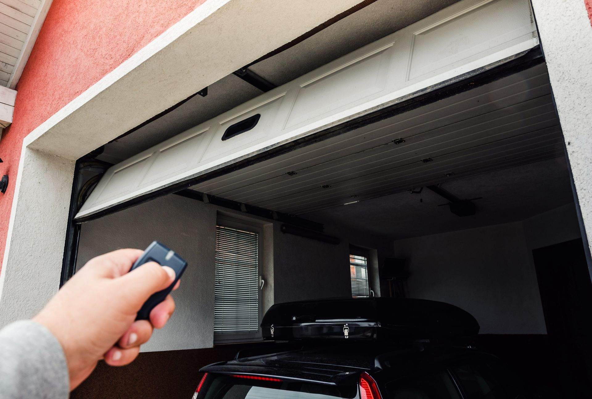 Focus sur une main et une télécommande qui ouvrent une porte de garage automatique