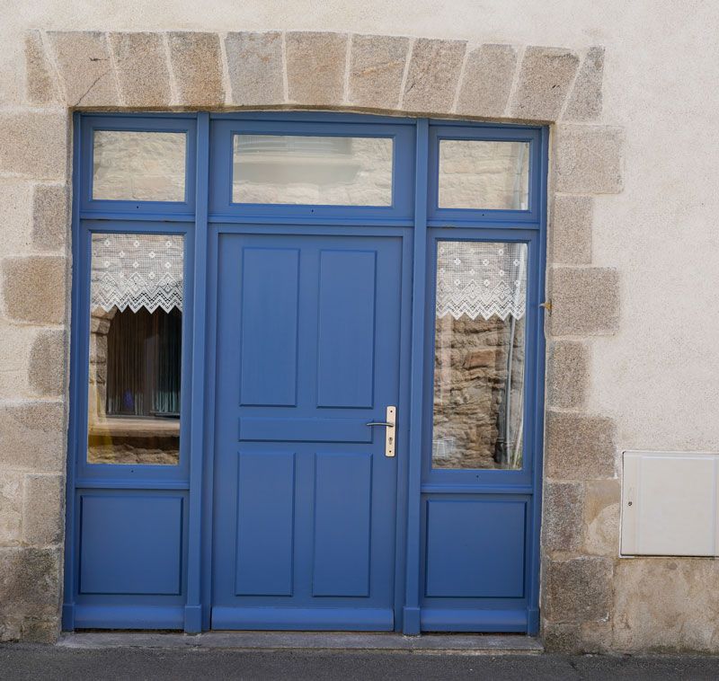 Une porte bleue en bois avec des fenêtres sur les côtés