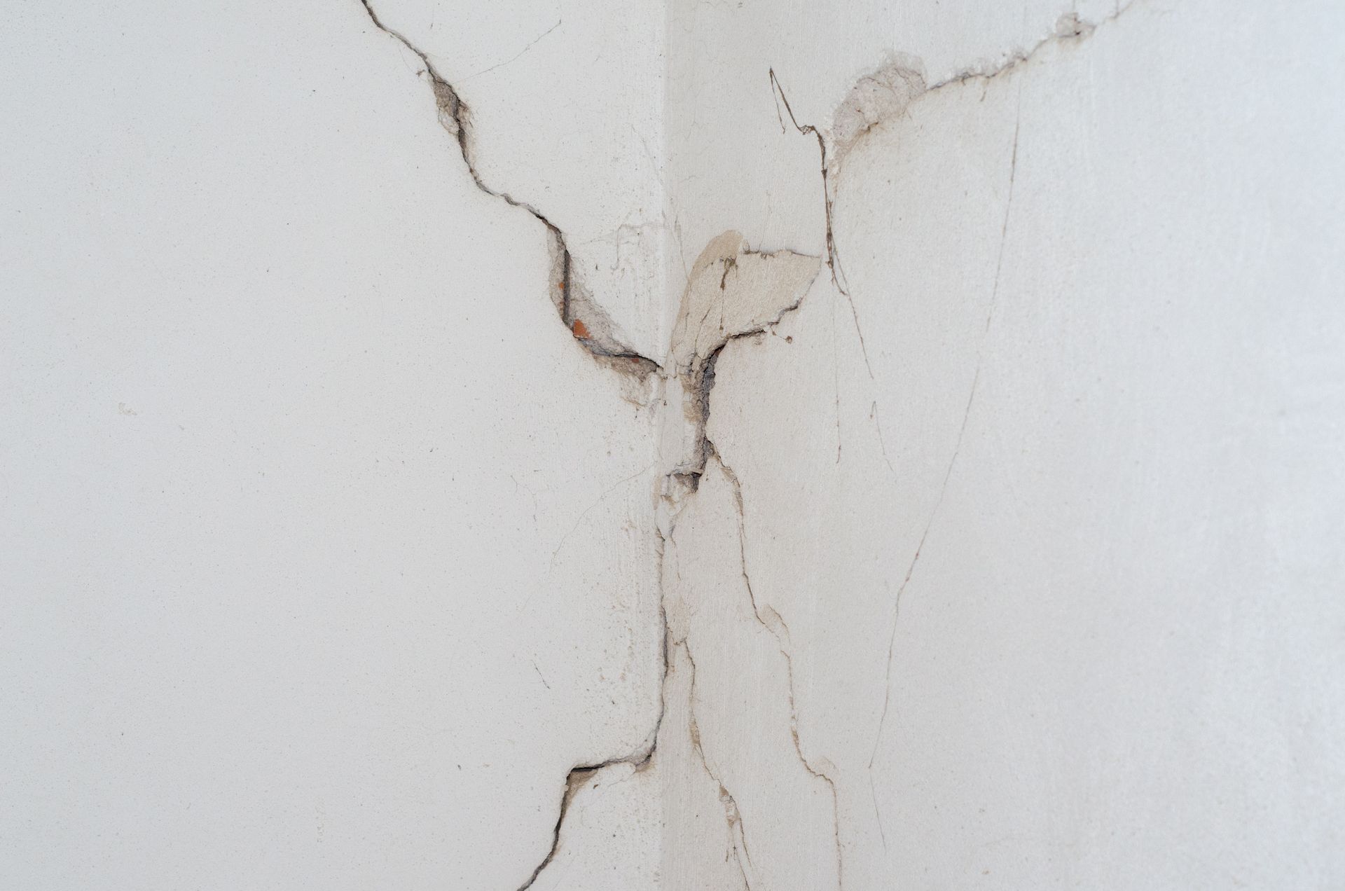 Un mur blanc fissuré dans un coin, avec des taches d'eau sombres.