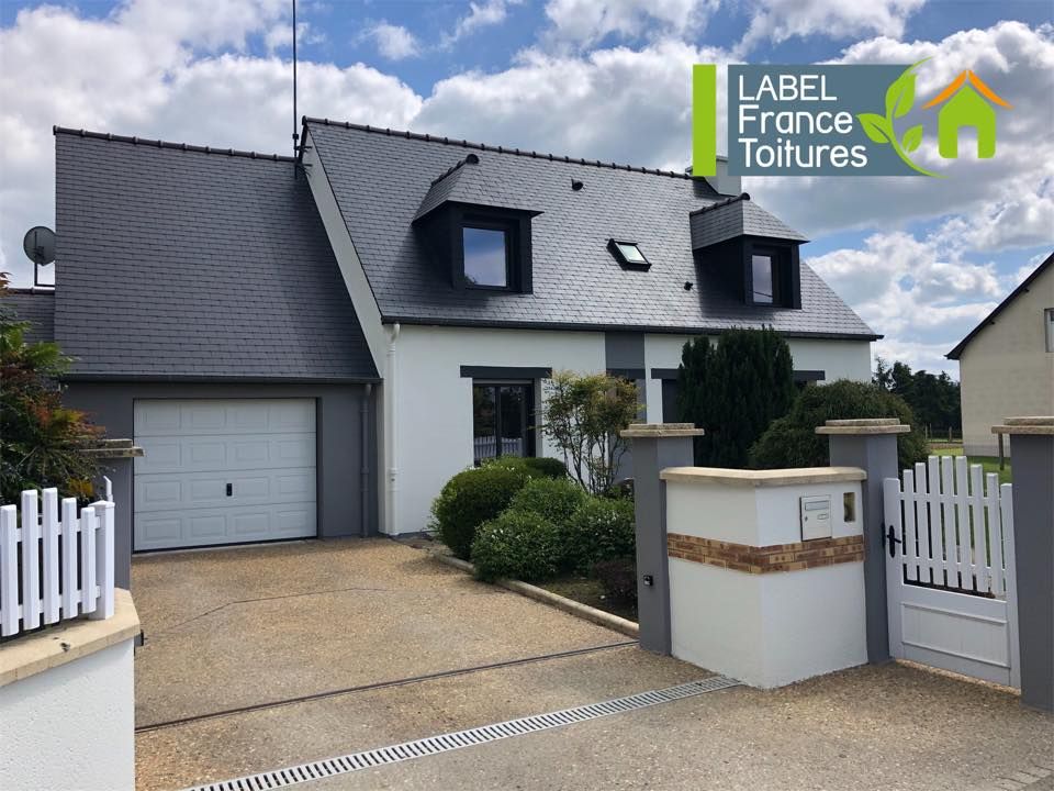 Maison blanche avec toit gris, lucarnes et garage ; allée, portail et logo de l'entreprise en haut à droite.