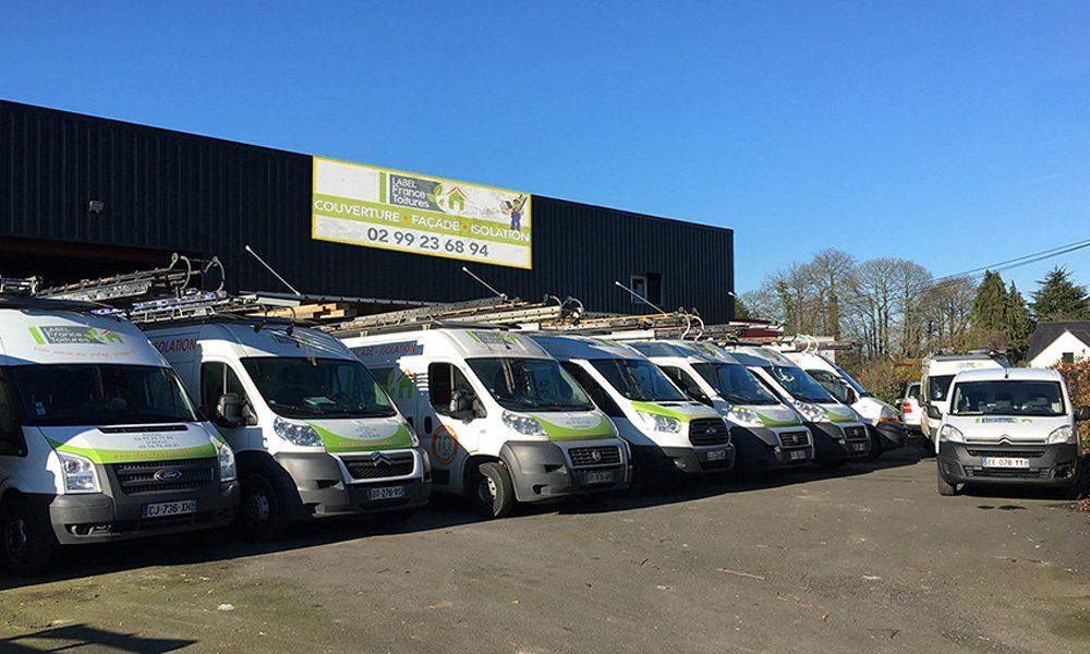 Une rangée de fourgonnettes blanches de l'entreprise garées devant un bâtiment par une journée ensoleillée.