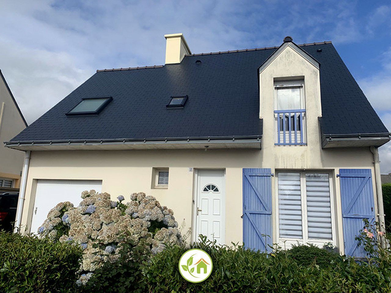 Maisonnette avec un toit bleu foncé, des volets bleu clair et une façade couleur crème.