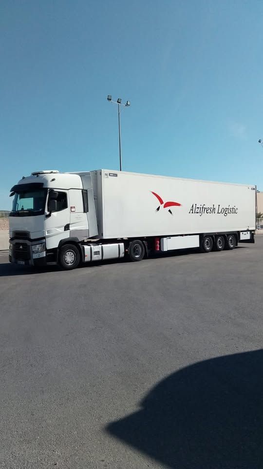 Un camión blanco con un pájaro rojo al costado está estacionado al costado de la carretera.