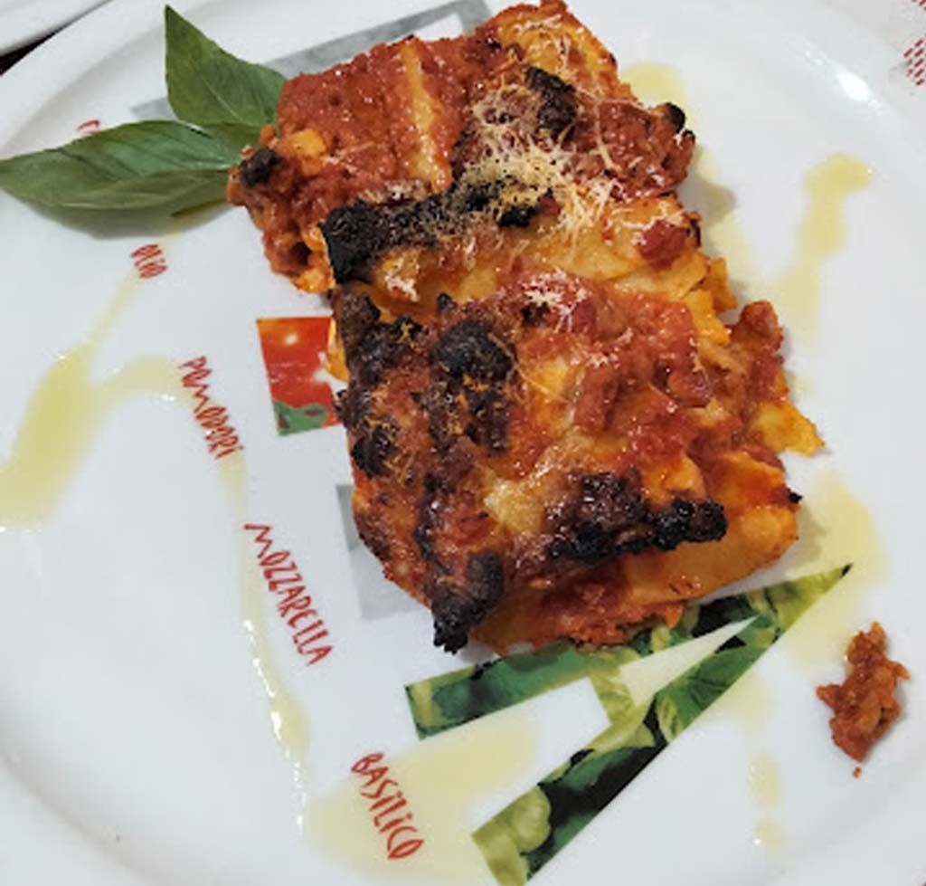 Un plato blanco con un trozo de lasaña encima.