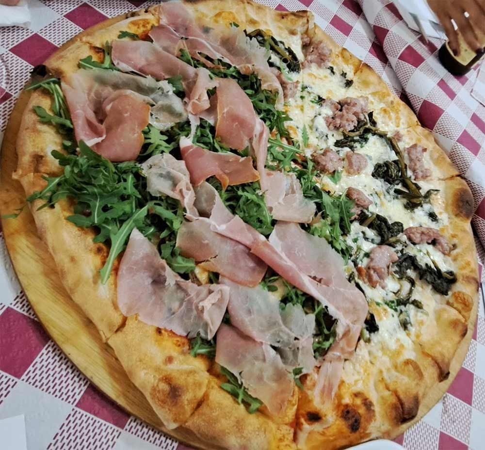 Una pizza con mucha carne y verduras encima.