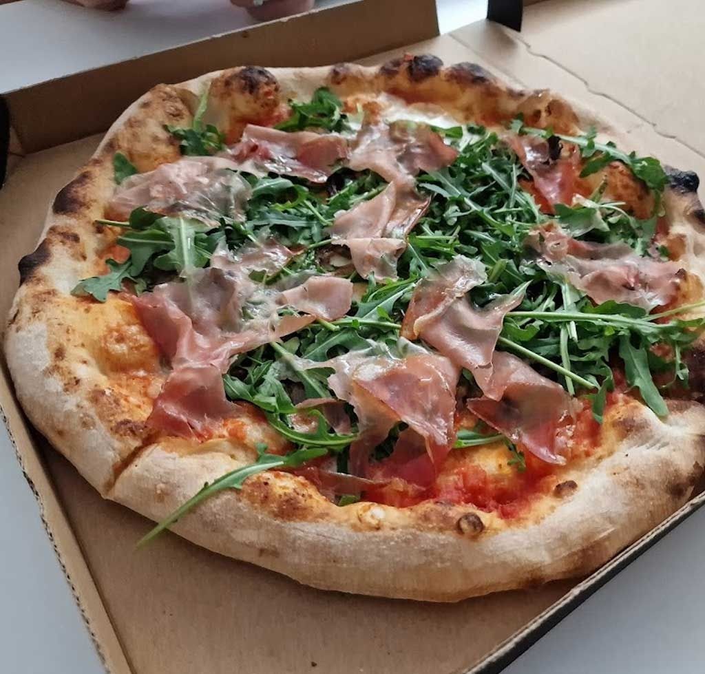 Una pizza con muchos ingredientes está en una caja de cartón.