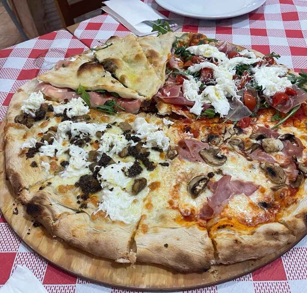 Una pizza en una bandeja de madera sobre un mantel a cuadros.