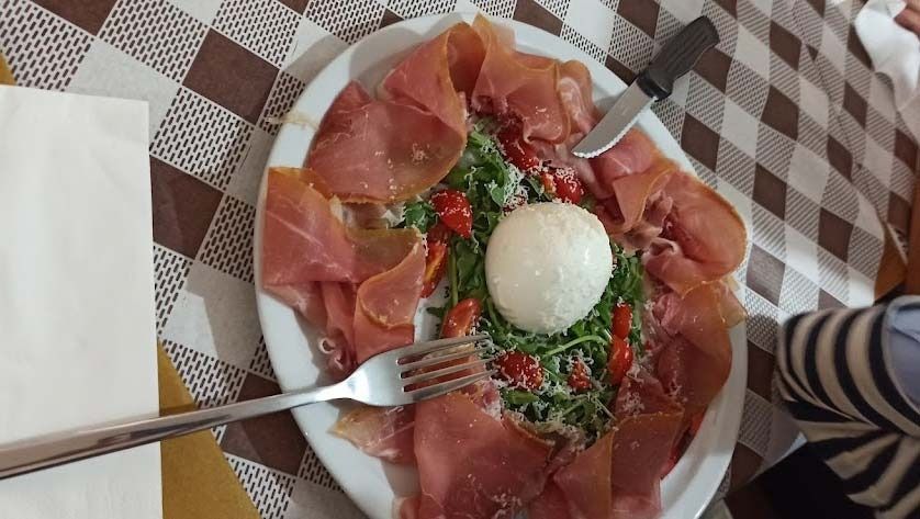 Un plato de carne y verduras con un tenedor sobre una mesa.