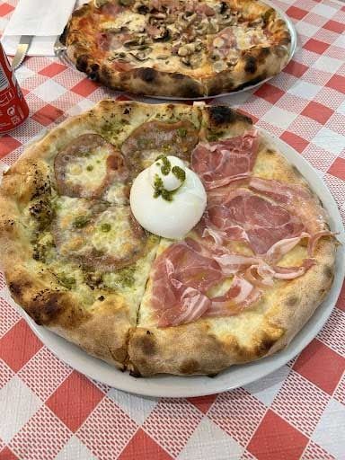 Una pizza está colocada en un plato blanco sobre un mantel a cuadros.