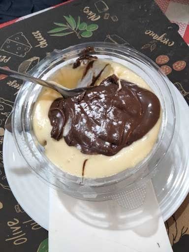 Un recipiente con comida y una cuchara dentro, sobre una mesa.