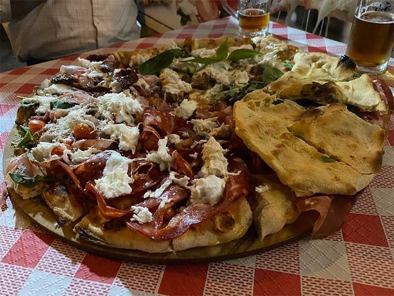 Una pizza con diferentes ingredientes está colocada sobre un mantel a cuadros.