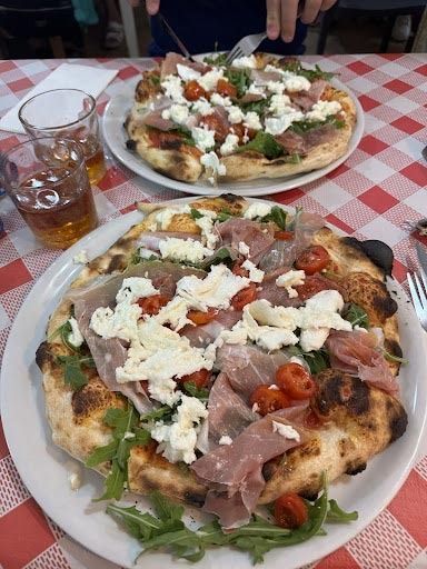 Hay dos pizzas en platos sobre un mantel a cuadros.