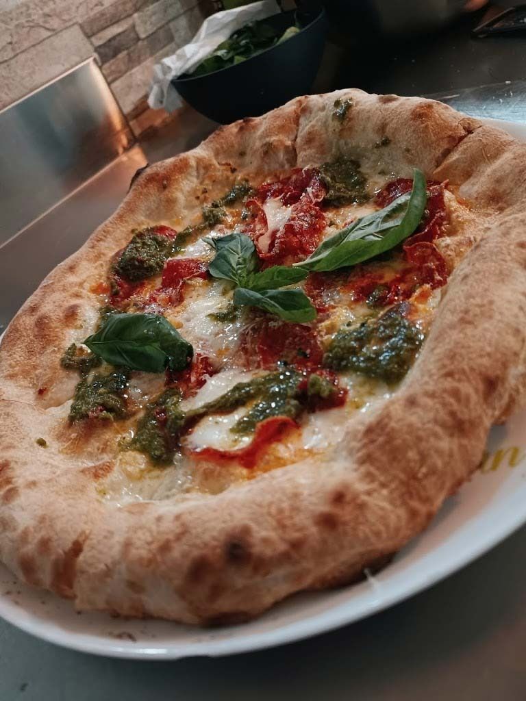 Una pizza está colocada en un plato blanco sobre una mesa.