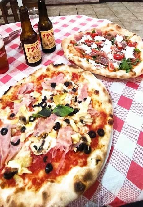 Dos pizzas están colocadas sobre un mantel a cuadros sobre una mesa.
