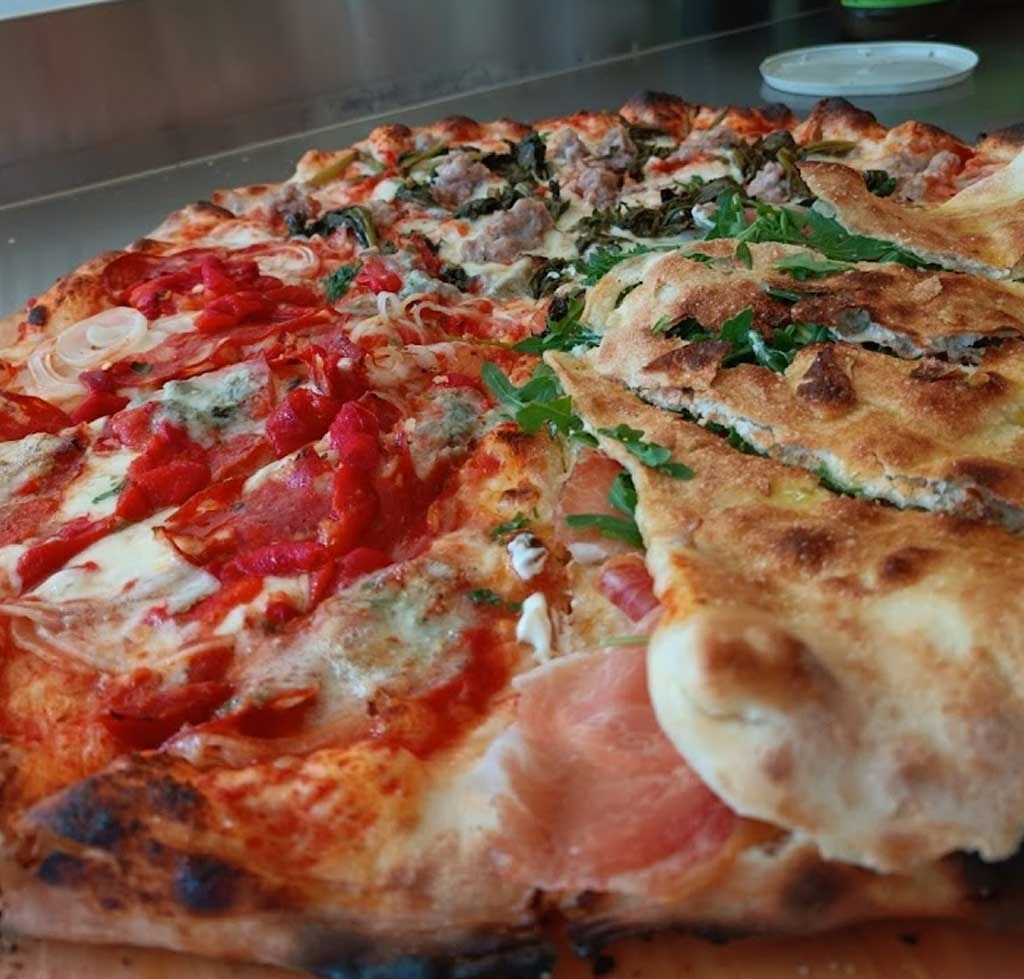 Una pizza con diferentes ingredientes está sobre una mesa.