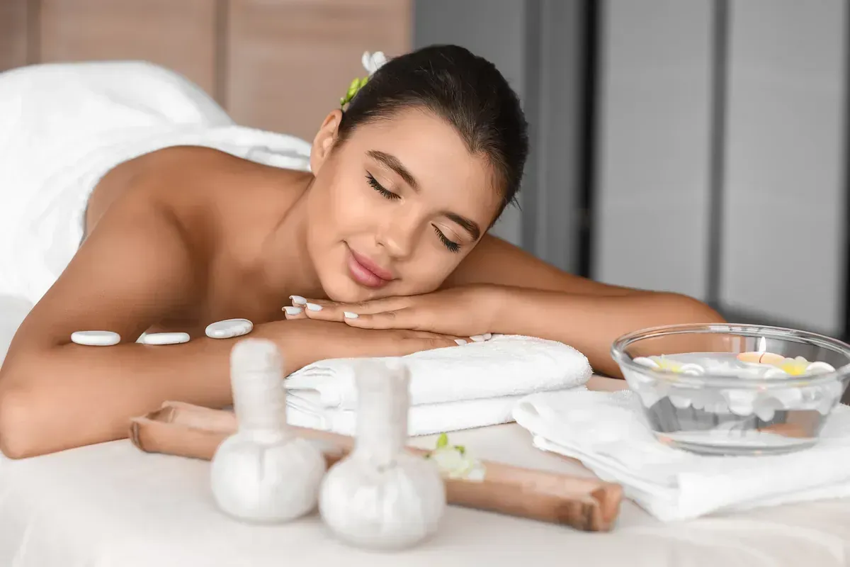 Una mujer está acostada en una cama en un spa con los ojos cerrados.