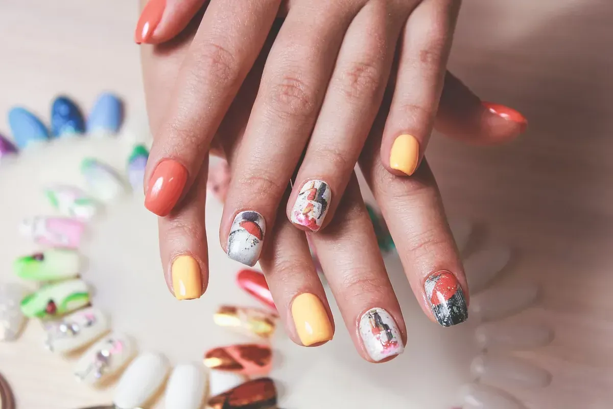 Un primer plano de las uñas de una mujer con diferentes colores de esmalte de uñas.
