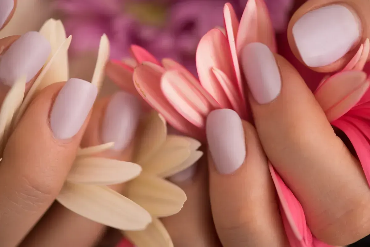 Un primer plano de las uñas de una mujer sosteniendo flores.