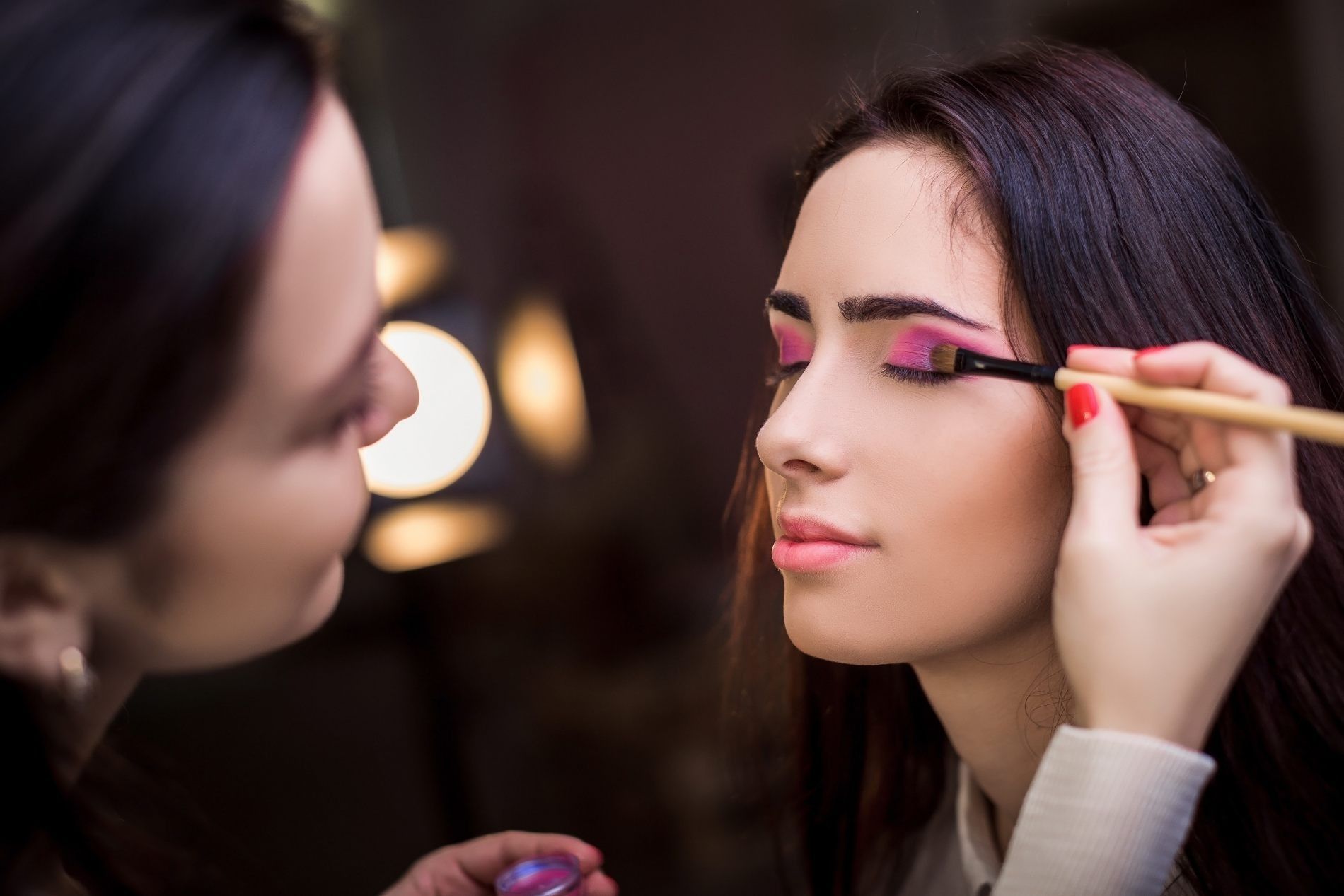 Una mujer se está maquillando con un maquillador.