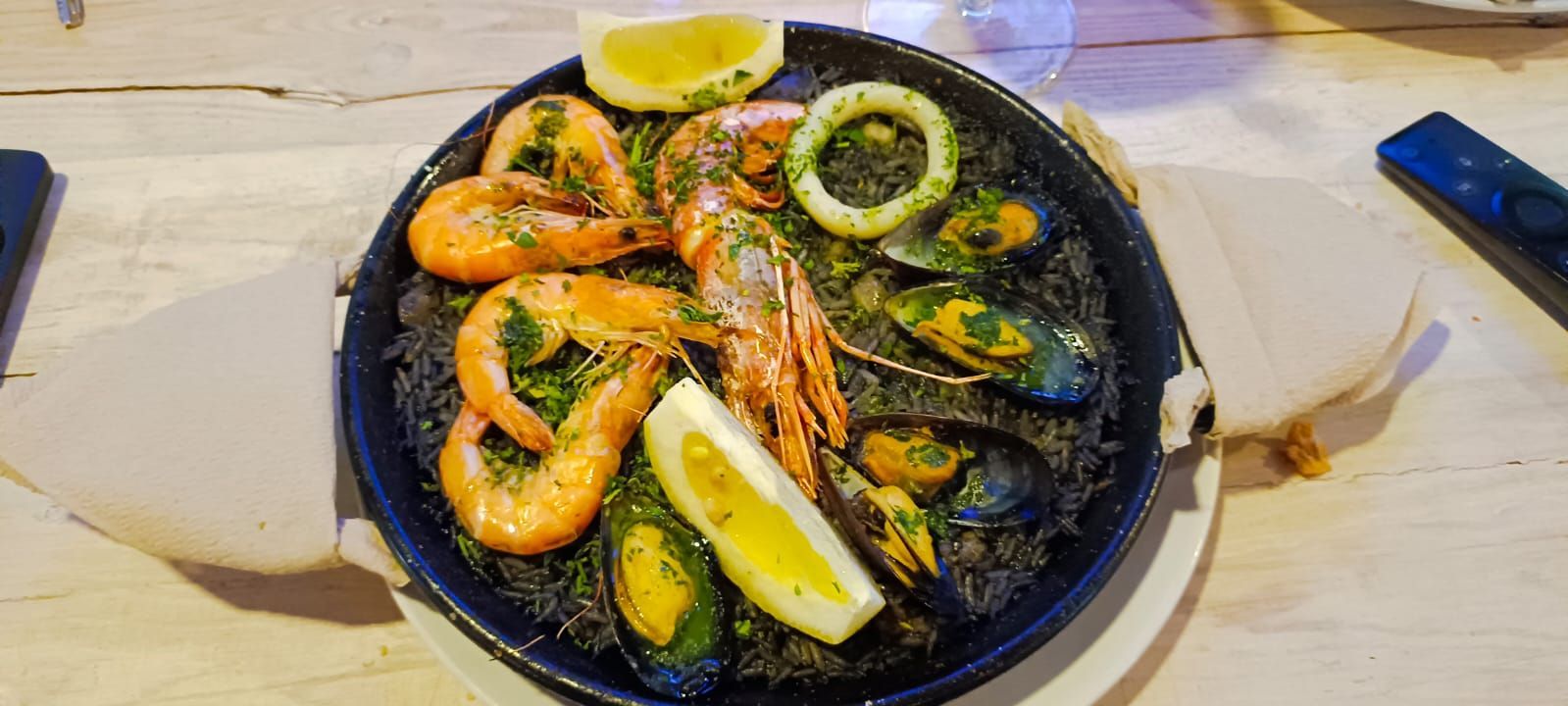 Un plato de comida con camarones, mejillones y limón sobre una mesa.