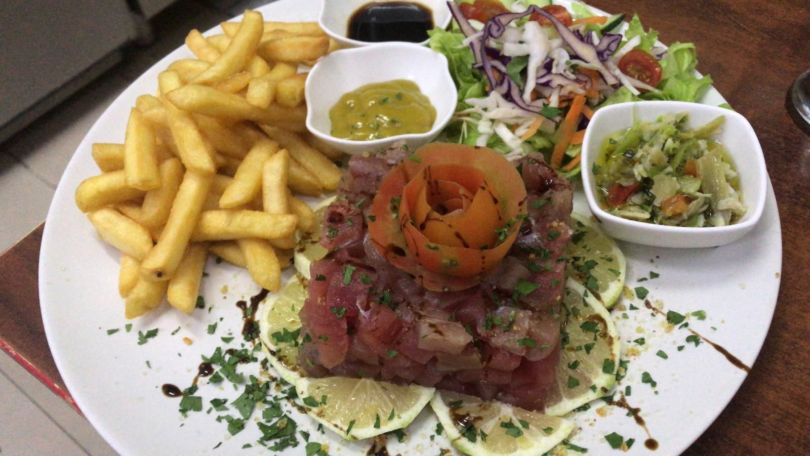 Un plato de comida con patatas fritas y una ensalada en una mesa.