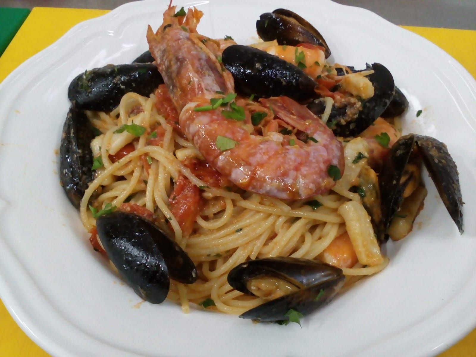 Un plato blanco cubierto con espaguetis, mejillones y camarones.