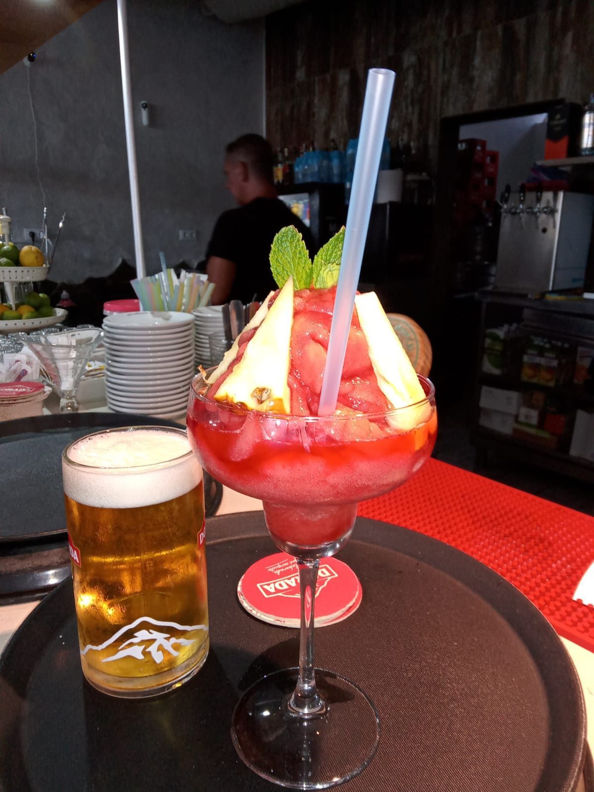 Una bebida en una copa de martini junto a un vaso de cerveza.