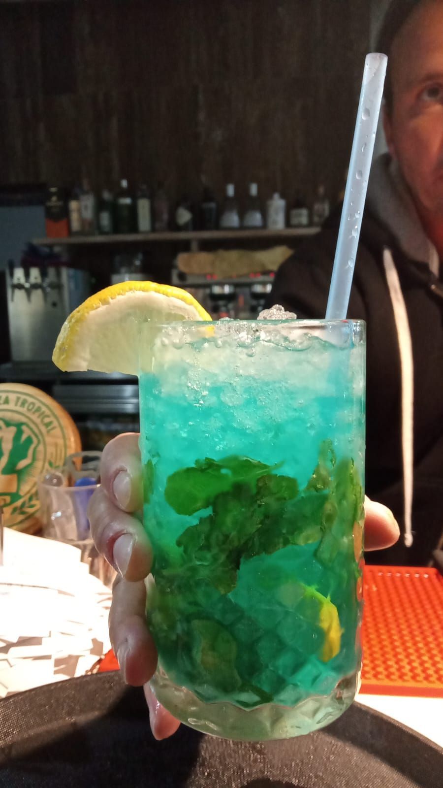 Una persona sostiene una bebida azul con una pajita.