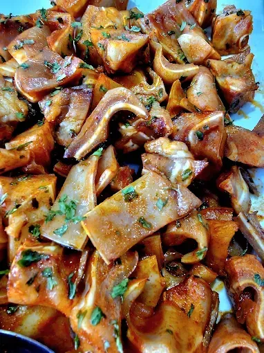 Orejas de cerdo cocidas, doradas con especias y hierbas, vista de cerca.