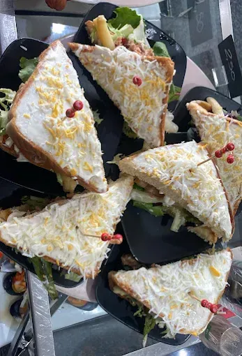 Sándwiches en platos negros, adornados con queso rallado y palillos.