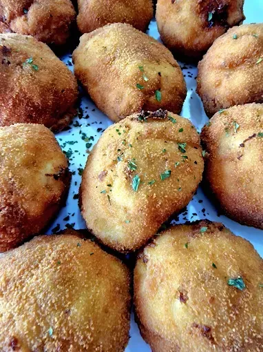 Una persona sostiene una bandeja de cucharas llenas de comida.