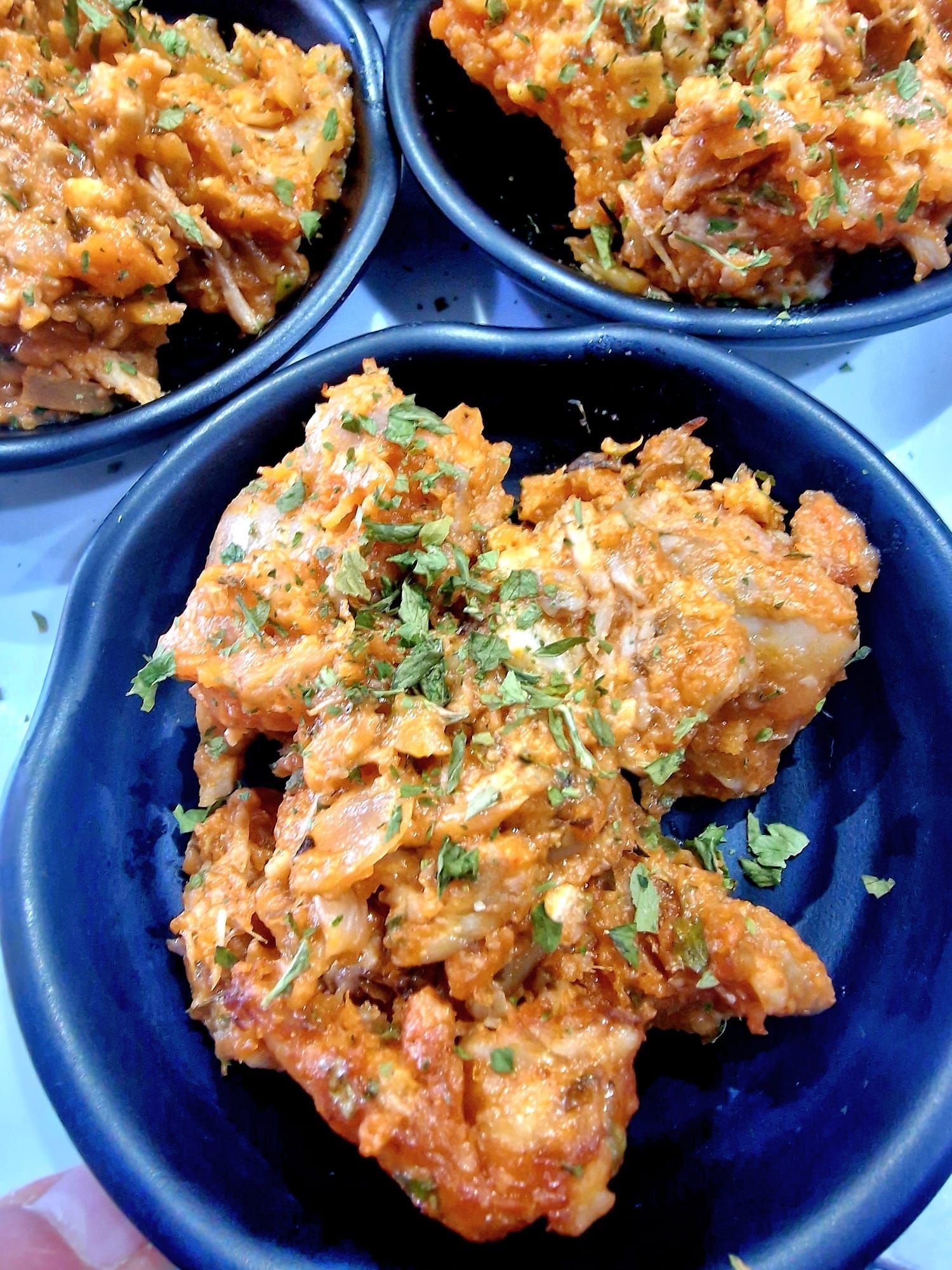 Una persona sostiene una bandeja de cucharas llenas de comida.