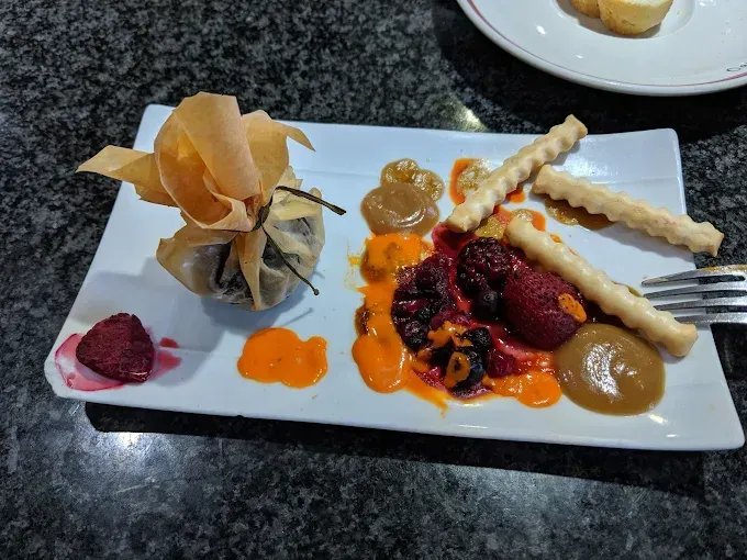 Un plato de ostras en hielo junto a una taza de sopa en una mesa.