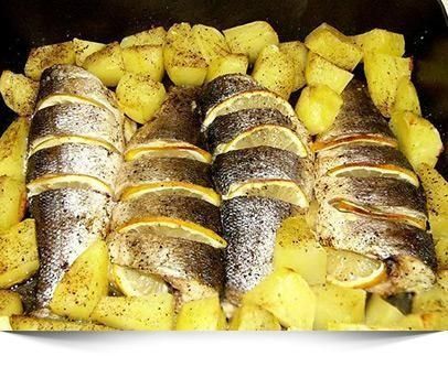 Tres peces están sentados encima de patatas en una sartén.