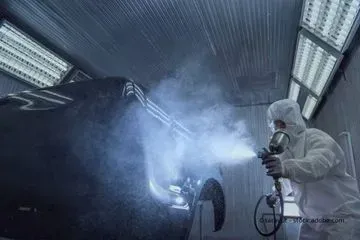 Person im Schutzanzug besprüht ein Auto, KFZ HAUNER MEISTERBETRIEB