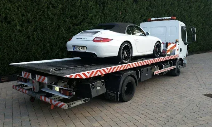 Porsche blanco descapotable en una grúa de plataforma. 