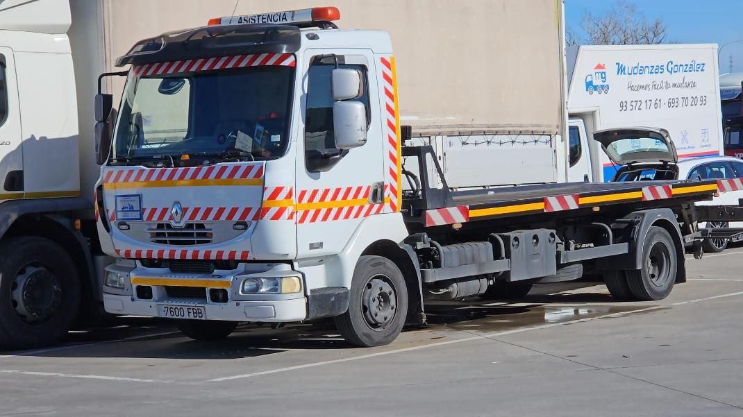 Grúa blanca con marcas de seguridad de rayas naranjas y blancas, estacionada.