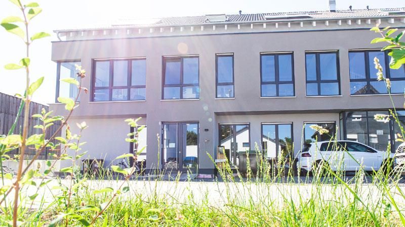 Ein Gebäude mit vielen Fenstern und einem davor geparkten Auto