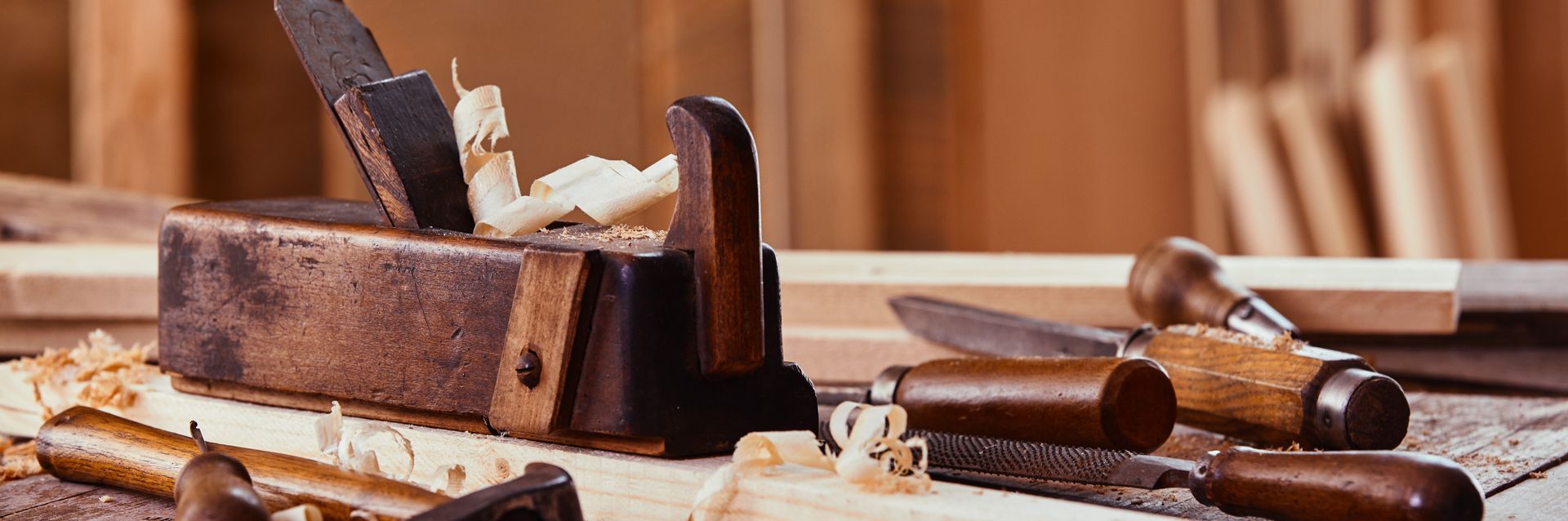 Outils de menuiserie sur une surface en bois, notamment un rabot à main et des ciseaux à bois avec des copeaux.