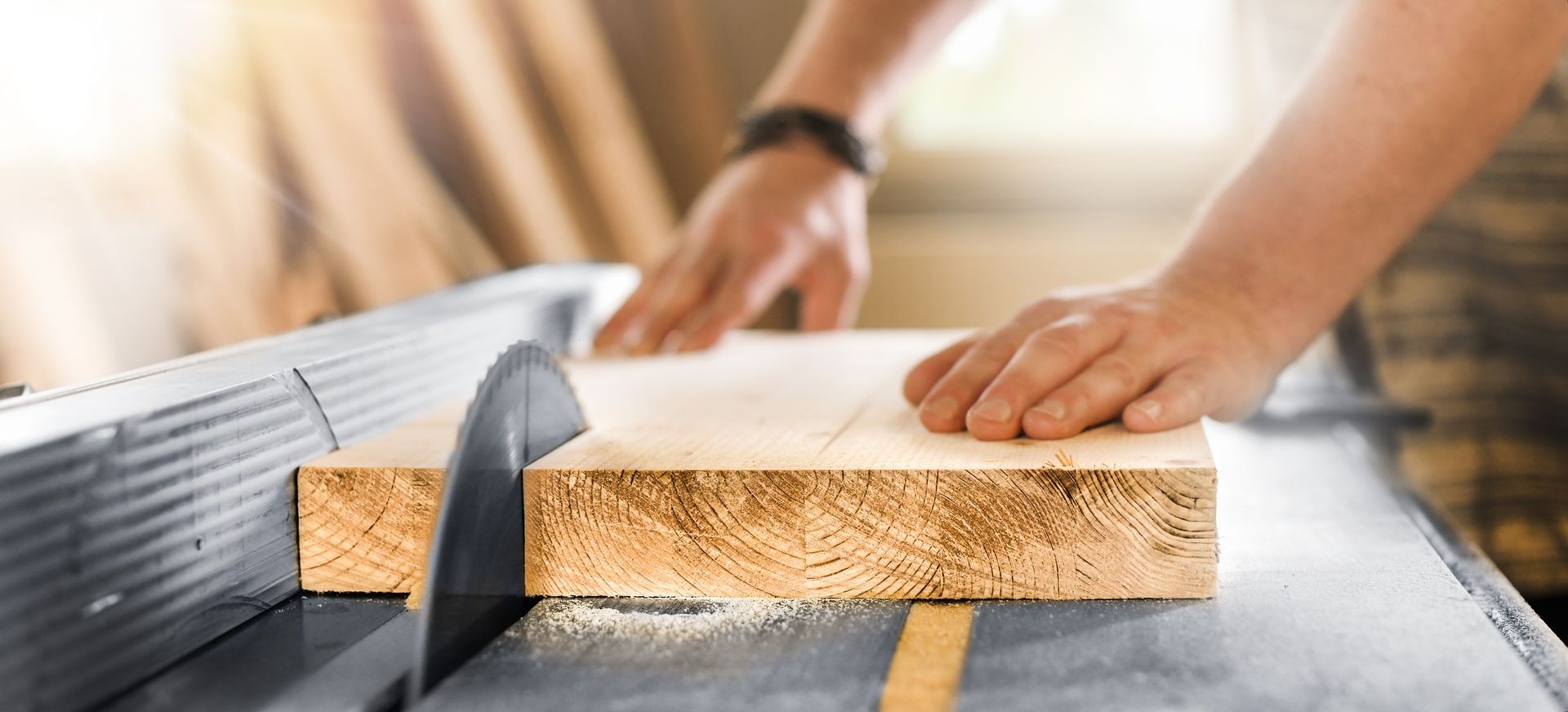 Une personne utilise une scie circulaire pour couper une planche de bois dans un atelier.