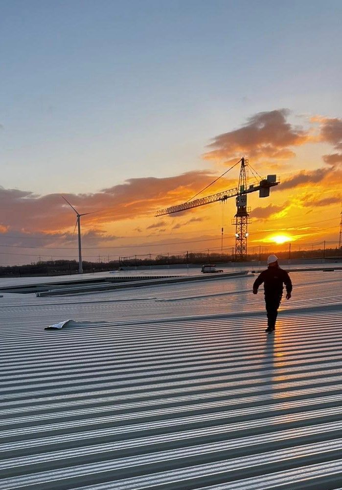 Bei Sonnenuntergang läuft ein Mann auf einem Dach . Im Hintergrund ist ein Kran zu sehen.