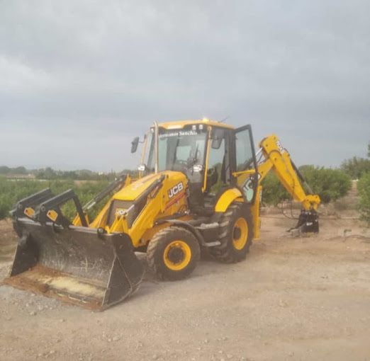 Un tractor amarillo está estacionado en un campo de tierra.