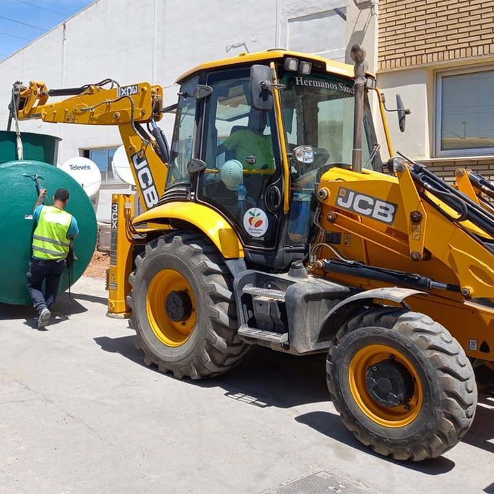 Un tractor JCB amarillo está estacionado frente a un edificio.